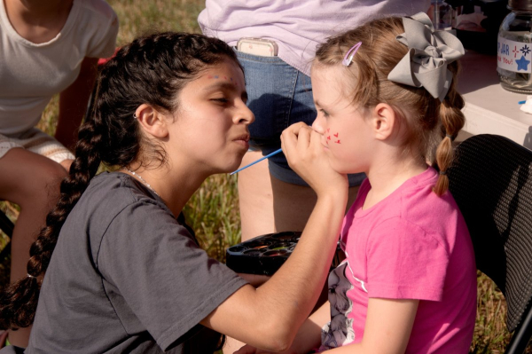A Key Club member concentrates while adding a fun face painting to a fellow festival-goer.