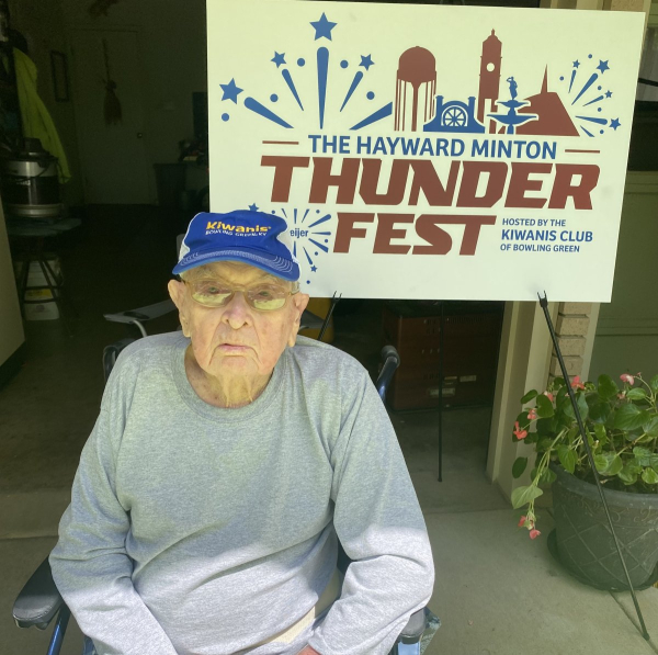 Hayward Minton, longtime Kiwanian and community leader, sits proudly in front of the newly unveiled Thunderfest banner that now bears his name—recognizing 65 years of dedication to service and community spirit.